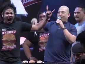 Ricardo "Rix Terabite" Francisco, left, reacts after breaking the Guinness World Record for the most hamburgers eaten in one minute on Monday. (Guinness World Record/YouTube)