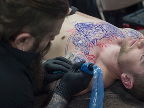 Chris Rhyason of Sterling Skull studio in Grande Prairie inks Beau Sheane at the Edmonton Expo Centre. The Edmonton Tattoo and Arts show featured over 250 exhibitors live entertainment on April 1, 2017. Photo by Shaughn Butts / Postmedia