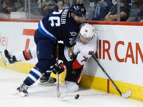 Winnipeg Jets forward Blake Wheeler (26) knocks Ottawa Senators' defenceman Mark Borowiecki off the puck in Winnipeg on Saturday, April 1, 2017. (THE CANADIAN PRESS/John Woods)