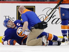 A trainer checks on New York Islanders forward John Tavares after he was injured against the New Jersey Devils Friday, March 31, 2017, in New York. (AP Photo/Frank Franklin II)