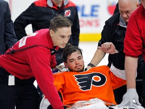 Philadelphia Flyers goalie Michal Neuvirth gives a thumbs-up as he is taken off the ice on a stretcher after collapsing during a game against the New Jersey Devils Saturday, April 1, 2017, in Philadelphia. (AP Photo/Tom Mihalek)