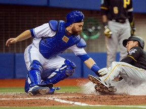 Pittsburgh Pirates’ Adam Frazier, right, is tagged out at home by Blue Jays catcher Russell Martin in Montreal on Friday, March 31, 2017. (THE CANADIAN PRESS/Paul Chiasson)