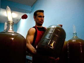 In this March 30, 2017 photo, winemaker Orestes Esteves moves a wine jug, at his home in Havana, Cuba. The winery started by his father who is also named Orestes, tends to 300 jugs containing five gallons of wine apiece. The main ingredient is Cuban grapes, but added flavors include tropical fruits and vegetables of virtually every variety. (AP Photo/Ramon Espinosa)