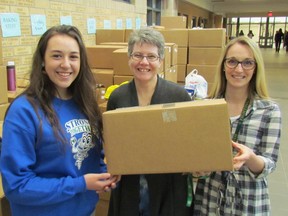 Holding one of the boxes of food students and other volunteers collected on the weekend during St. Patrick's Catholic High School's annual Cyclone Aid food drive Monday are, from left, Grade 11 student Julia Pagotto, teacher Karen Laucke and teacher Vanessa Borody. The food will be delivered this week to the Inn of the Good Shepherd for its Sarnia food bank. (Paul Morden/Sarnia Observer/Postmedia Network)