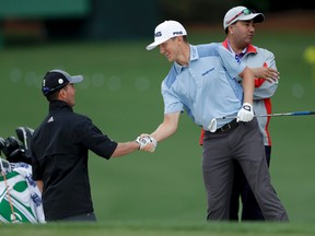Canadians Mackenzie Hughes (right) and Mike Weir shake hands on the driving range at the Masters in Augusta, Ga., yesterday. (AP)