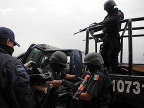 In this June 26, 2009 file photo, seized weapons from alleged members of the Beltran Leyva drug cartel are taken away by federal agents after a press conference in Mexico City. (AP Photo/Alexandre Meneghini, File)