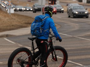 A cyclist rides in congested rush hour traffic at the intersection of Terwillegar Drive and 40 Avenue in Edmonton on Friday, March 24, 2017. Ian Kucerak / Postmedia