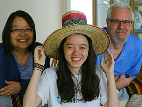 Isabel Schuppli (18-years-old) tries on a traditional Ethiopian tribal hat that she picked up recently from a family trip to Ethiopia. Beside her is her mother Julia Lee-Schuppli (left) and father James Schuppli (right) at their home in Edmonton. Isabel was diagnosed with cancer in 2015 and used her Children's Wish Foundation wish to travel to Ethiopia to visit the girl that her family sponsors through Compassion Canada. (PHOTO BY LARRY WONG/POSTMEDIA)