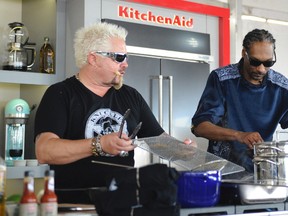 This Feb. 26, 2017 photo made available by WorldRedEye.com, shows rapper Snoop Dogg, right, and Chef Guy Fieri, cooking together during a demonstration at the South Beach Wine & Food Festival in Miami Beach, Fla. Rappers Snoop, Action Bronson and Rev Run are ushering the culinary world into an era where shows like ““Martha and Snoop’s Potluck Dinner Party” are a hit and rappers like 2 Chainz drop cookbooks along with their albums. (Ryan Troy/WorldRedEye.com via AP)