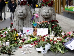 Flowers and candles are placed around stone lions near the department store Ahlens following a suspected terror attack in central Stockholm, Sweden, Saturday, April 8, 2017. (AP Photo/Markus Schreiber)