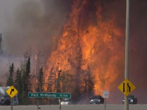 A convoy of evacuees from Fort McMurray, Alberta drive past wildfires that are still burning out of control as they leave the city Saturday, May 7, 2016.