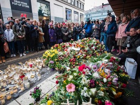 People react during a minute of silence to commemorate the victims of Friday's terror attack at a makeshift memorial near the site where a truck drove into Ahlens department store in Stockholm, Sweden, on April 10, 2017.
