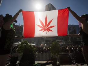 Two people hold a modified design of the Canadian flag with a marijuana leaf in in place of the maple leaf during the "420 Toronto" rally in Toronto, April 20, 2016. (THE CANADIAN PRESS/Mark Blinch)