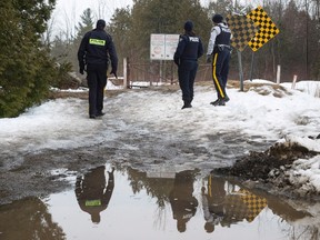 Three RCMP officers look over to the United States on the border with Canada where many asylum seekers have been crossing the United States near Hemmingford, Que. on March 28, 2017. (Paul Chiasson/The Canadian Press)