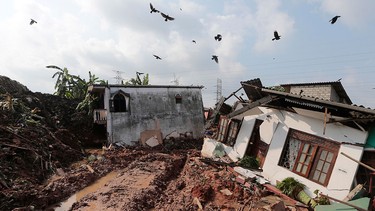 Crows fly over a row of houses buried by a collapse of a garbage dump in Meetotamulla, on the outskirts of Colombo, Sri Lanka, Saturday, April 15, 2017. A part of the garbage dump that had been used in recent years to dump the waste from capital Colombo collapsed destroying houses, according to local media reports. (AP Photo/Eranga Jayawardena)