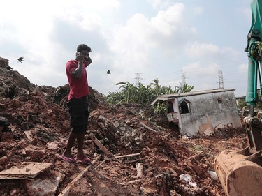 A Sri Lankan man speaks on his mobile phone at the site of buried houses in a collapse of a garbage dump in Meetotamulla, on the outskirts of Colombo, Sri Lanka, Saturday, April 15, 2017. A part of the garbage dump that had been used in recent years to dump the waste from capital Colombo collapsed destroying houses, according to local media reports. (AP Photo/Eranga Jayawardena)
