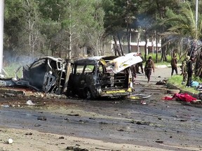 This frame grab from video provided by the Thiqa News Agency, shows rebel gunmen at the site of a blast that damaged several buses and vans at the Rashideen area, a rebel-controlled district outside Aleppo city, Syria, Saturday, April. 15, 2017. (Thiqa News via AP)