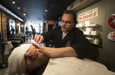 Barber Frank Manicapelli of Driven Barber on Dundas St. W., gives a shave and a hair cut to Eugene Dvimyi of Toronto on his first experience at the traditional barbershop transformed from originally a car garage by car enthusiast Bill Halkiw. Friday April 7, 2017. (Stan Behal/Toronto Sun)