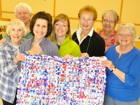 Holding a plastic mat made entirely of used milk bags are some members of the Upper Thames Missionary Church (UTMC) congregation, Pat Britton (left), Ron Boonstra, Alli Schultz, Lisa Granja, Anne Towle, Ruth Boonstra and Marilyn French. The church is host to a series of work bees to make the mats twice a month, cut and tied together, for those in need in South Africa. ANDY BADER/MITCHELL ADVOCATE