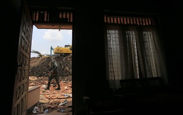 A Sri Lankan military rescue worker walking in the site of garbage mound collapse is seen from inside one of the adjacent residential buildings in Meetotamulla, on the outskirts of Colombo, Sri Lanka, Colombo, Sri Lanka, Monday, April 17, 2017. Rescuers on Monday were digging through heaps of mud and trash that collapsed onto a clutch of homes near a garbage dump outside Sri Lanka's capital, killing dozens and possibly burying dozens more. (AP Photo/Eranga Jayawardena)