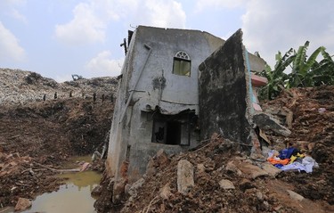 Sri Lankan army soldiers, background on left, search on the mound of garbage as a damaged house is seen in the foreground following a garbage collapse in Meetotamulla, on the outskirts of Colombo, Sri Lanka, Colombo, Sri Lanka, Monday, April 17, 2017. Rescuers on Monday were digging through heaps of mud and trash that collapsed onto a clutch of homes near a garbage dump outside Sri Lanka's capital, killing dozens and possibly burying dozens more. (AP Photo/Eranga Jayawardena)