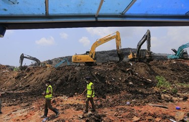 Sri Lankan police officers walk in the site of garbage mound collapse in Meetotamulla, on the outskirts of Colombo, Sri Lanka, Colombo, Sri Lanka, Monday, April 17, 2017. Rescuers on Monday were digging through heaps of mud and trash that collapsed onto a clutch of homes near a garbage dump outside Sri Lanka's capital, killing dozens and possibly burying dozens more. (AP Photo/Eranga Jayawardena)
