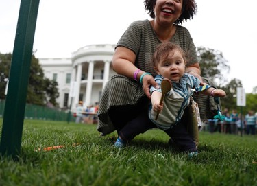 Children get a little help from parents as they cross the finish line during the White House Easter Egg Roll on the South Lawn of the White House in Washington, Monday, April, 17, 2017. President Donald Trump and first lady Melania Trump are set to host the official annual Easter egg roll at the White House. (AP Photo/Carolyn Kaster)
