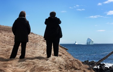 Lorraine Croft (left) and Sheila Condon from nearby Calvert, observe a large iceberg visible from the shore in Ferryland, an hour south of St. John's, Newfoundland on Monday, April 10, 2017. More icebergs have drifted into major shipping lanes off Newfoundland, forcing ships to go far out of their way to steer clear of the massive ice mountains." THE CANADIAN PRESS/Paul Daly ORG XMIT: PD440