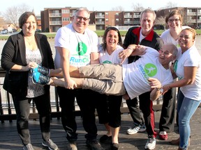 Angelo Ligori, who helped develop the RunCK Series, is hoisted by local run organizers, from left, Jenny Jackson, Tom Slager, Amy Wadsworth, Mark Childs, Alison McMahon and Michelle Robbins, during a meeting in Wallaceburg, Ont. on Tuesday April 11, 2017. (Ellwood Shreve/Chatham Daily News)