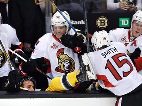 Senators’ Zack Smith sends Ryan Spooner of the Bruins into the Ottawa bench during the third period of last night’s Game 3 in Boston. AP