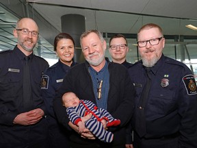Frank Rieckmann (middle), holding his grandson Kade Temke, with his life savers, Canadian Border Services Agency employees (left to right) Tim Boulton, Tina Buffalo, Dan Rawlyk and Darren Dahlseide at the Edmonton International Airport on April 18, 2017.