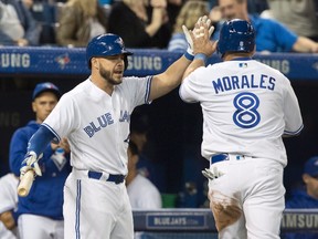 Kendrys Morales of the Blue Jays (right) gets a high five from Russell Martin after scoring a first-inning run. (CP)