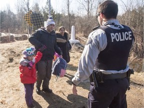 A family, who claim to be from Colombia, are arrested by an RCMP officer as they cross the border from New York into Canada, February 28, 2017 in Hemmingford, Quebec. THE CANADIAN PRESS/Ryan Remiorz