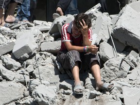 A young Syrian boy cries as he sits on the rubble after a missile fired by Syrian government forces hit a residential area in the Maghayir district in the old quarter of the northern Syrian city of Aleppo in July 2015. (Postmedia Network)