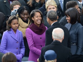 US President Barack Obama greets his daughter Malia as his wife Michelle (R) and daughter Sasha (L) look on as he arrives to take the oath of office during the 57th Presidential Inauguration ceremonial swearing-in at the US Capitol on January 21, 2013 in Washington, DC. AFP PHOTO / Stan HONDASTAN HONDA/AFP/Getty Images