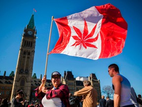 This file photo taken on April 20, 2016 shows a woman waving a flag with a marijuana leaf on it next to a group gathered to celebrate National Marijuana Day on Parliament Hill in Ottawa. CHRIS ROUSSAKIS/AFP/Getty Images