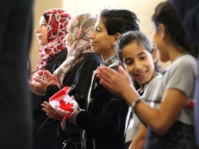 Mutaz Abu-Khader, 12, centre, grins from ear to ear after hearing himself officially declared a Canadian citizen as he stands with his family from Jordan during a citizenship ceremony in Ottawa on Jan. 3. (Julie Oliver/Postmedia Network)