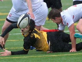 Glendale's Connor Winrow keeps his eye on the ball after being tackled by Medway's Liam McDonald during an exhibition rugby tournament at City Wide Field on Wednesday April 19, 2017. Medway won the 30-minute game 24-0. (MORRIS LAMONT, The London Free Press)