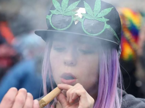 A woman smokes marijuana on Parliament Hill on 4/20 in Ottawa, Ontario, April 20, 2017.  Polling released Thursday showed strong support in Canada for a government drive to legalize recreational use of marijuana, but many would like the proposed minimum age for consumption to be raised. Sixty-three percent of respondents told the Angus Reid Institute they support legalization. LARS HAGBERG AFP/Getty Images