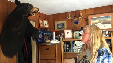 In this April 5, 2017 photo, longtime Tiller resident Paula Ellis shows off a bear head hanging on the wall in her home in Tiller, Ore. Ellis spent her childhood in Tiller hunting and riding horses and now worries about what will happen to the tiny, dying timber town. Tiller, a dot on a map in remote southwestern Oregon, is for sale for $3.5 million and the elementary school is for sale separately for $350,000.  (AP Photo/Gillian Flaccus)