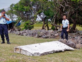 In this July 29, 2015 file photo, French police officers look over a piece of debris from a plane in Saint-Andre, Reunion Island. The wing was later found to be from missing Malaysia Airlines Flight 370 that went missing March 8, 2014, with 239 people aboard while flying from Kuala Lumpur to Beijing. Analysis of a genuine Boeing 777 wing flap has reaffirmed experts' opinion that a missing Malaysian airliner most likely crashed north of an abandoned search area in the Indian Ocean, officials said Friday, April 21, 2017. The search for Malaysia Airlines Flight 370 ended in January after a deep-sea sonar scan failed to find any trace of the plane. But research has continued in an effort to refine a possible new search. (AP Photo/Lucas Marie, File)