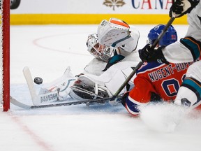 San Jose Sharks goalie Martin Jones, left, dives for the puck as Edmonton Oilers' Ryan Nugent-Hopkins crashes into him during overtime NHL hockey round one playoff action in Edmonton, Thursday, April 20, 2017.