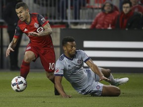 Toronto FC’s Sebastian Giovinco tries to evade a tackle by Chicago’s Juninho during Friday’s game. (JACK BOLAND/Toronto Sun)