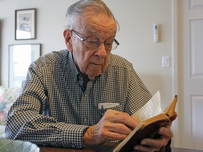 Bill Fitsell, at his home in Kingston on Saturday, reads the diary he wrote while serving in the Royal Canadian Navy during the Second World War. (Steph Crosier/The Whig-Standard)