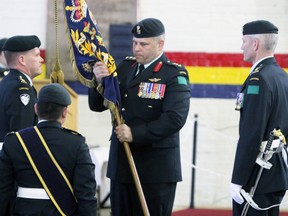 Lt.-Col. Joe Parkinson, left, hands over the colours of the Princess of Wales' Own Regiment to Col. John Valtonen and ultimately Lt.-Col. Steve Taylor, right, during the change of command ceremony at the Armouries on Sunday. (Steph Crosier/The Whig-Standard)