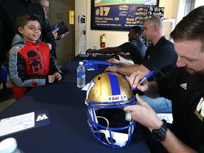 Frankie Rumore, 9, watches as Winnipeg Blue Bombers quarterback Matt Nichols signs a helmet for him during an autograph session in the Bomber Store at Investors Group Field in Winnipeg on Mon., April 24, 2017. Seated at the table with Nichols are Dominique Davis (left) and Dan LeFevour. Kevin King/Winnipeg Sun/Postmedia Network