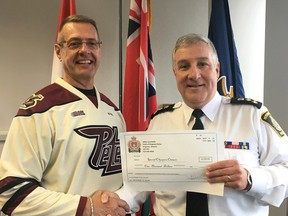 Kingston Police Chief Gilles Larochelle, left, presents a cheque in the amount of $1,000 for Ontario Special Olympics while wearing a Peterborough Petes jersey to Peterborough Police Chief Murray Rodd, the result of a lost bet on the results of a Ontario Hockey League playoff series between the two city's major junior teams. The presentation was made at Peterborough Police Headquarters on Tuesday April 25 2017. (Kingston Police photo)