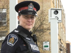 Sgt. Amanda Pfeffer who runs the London Police Traffic Management Unit stands next to a stop light camera installed by the city at Adelaide Street and Queens Avenue. (Mike Hensen/The London Free Press)