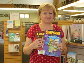 Library technician Dalene VanZyl holds Garfield and Simpsons comic book collections at the John Kenneth Galbraith Reference Library in Dutton Thursday afternoon. The Elgin County Library branch is one of ten participating in Free Comic Book Day May 6. (Laura Broadley/Times-Journal)