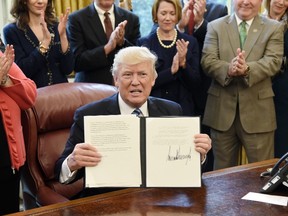 U.S. President Donald Trump shows his signature on the Memorandum on Aluminum Imports and Threats to National Security in the Oval Office on April 27, 2017 in Washington, DC. (Photo by Olivier Douliery - Pool/Getty Images)